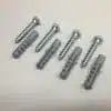 Silver screws and gray plastic anchors on table.